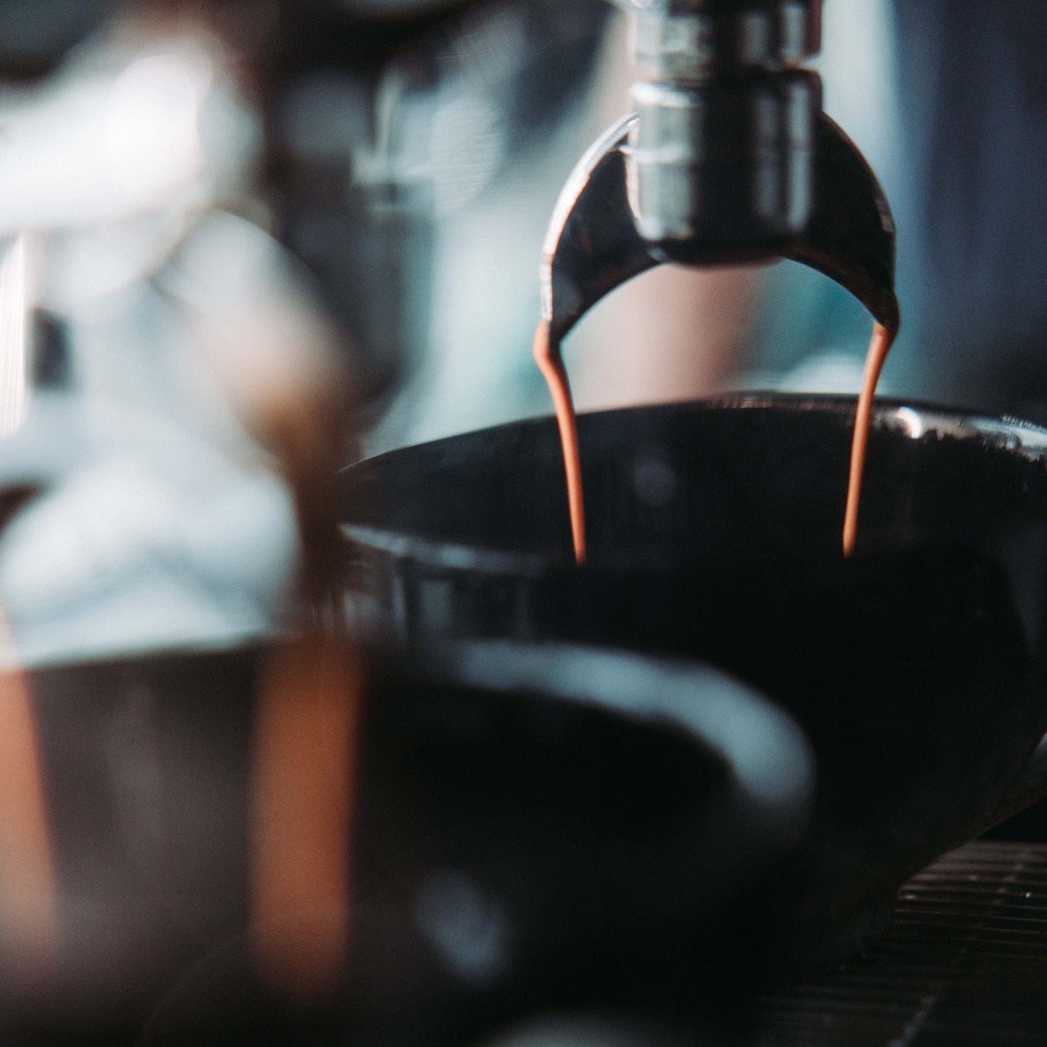 Coffee being poured from a machine into a black container.