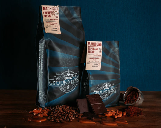 Two coffee bags from Ground Effect with coffee beans and chocolate on a dark background